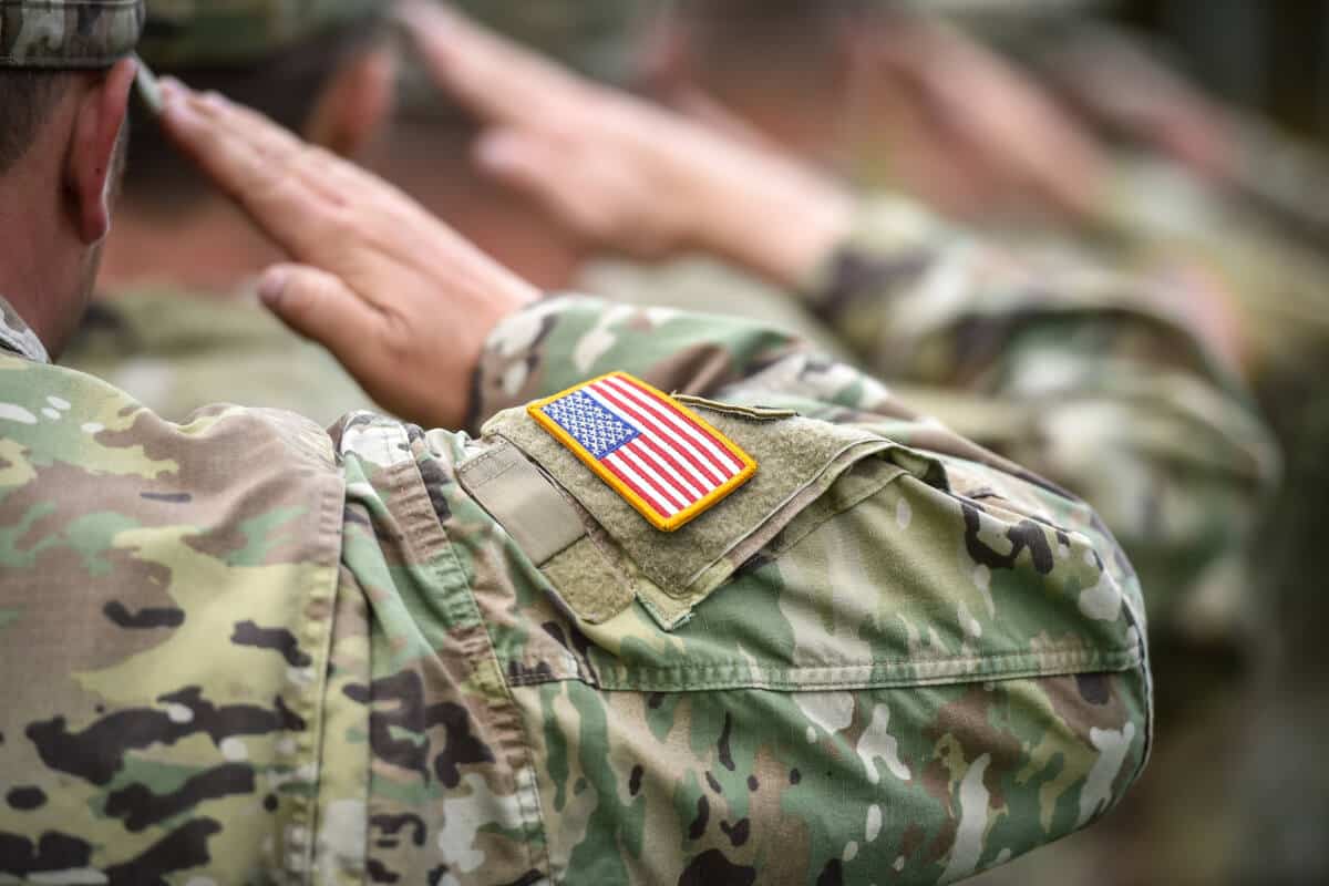 US military members in camo uniforms salute