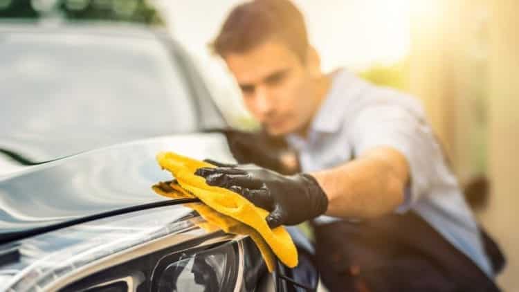 car detailer wiping down a car with a microfiber rag