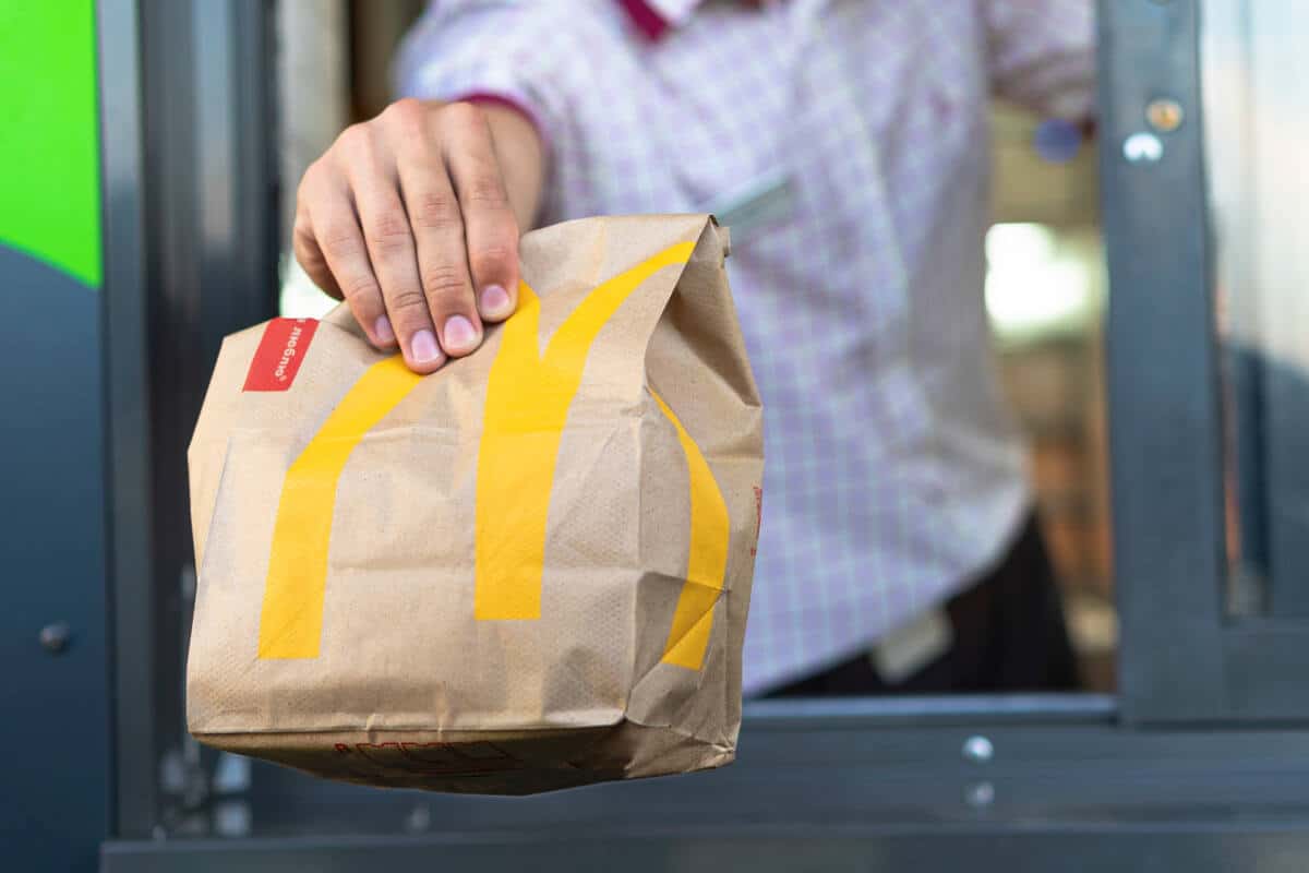 A worker passes a bag of McDonald’s out the drive-thru window.