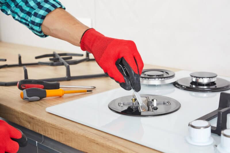 The technician adjusts the burner of a gas stove.