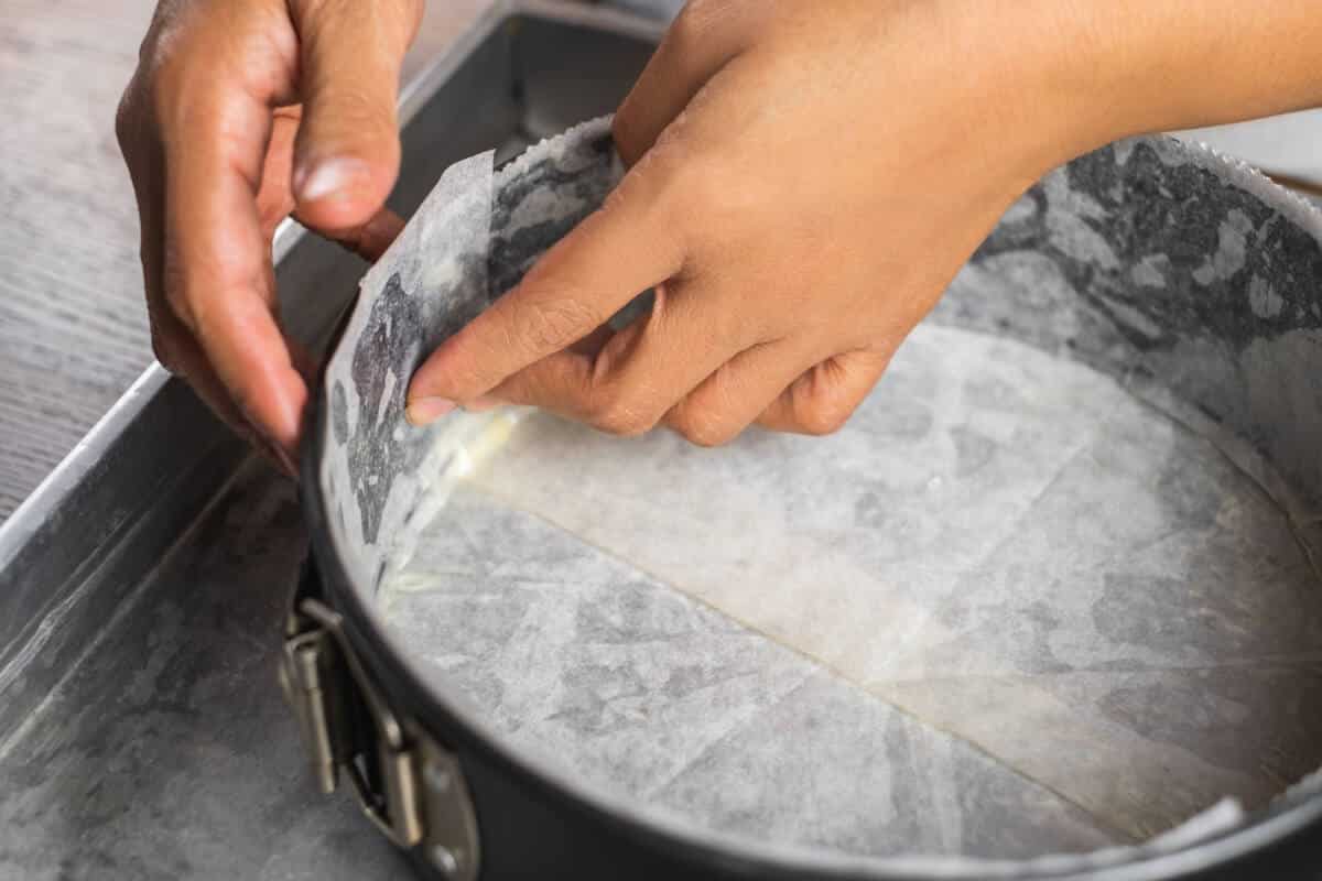 A cake tin line with wax paper and wrap in aluminum foil on a tray