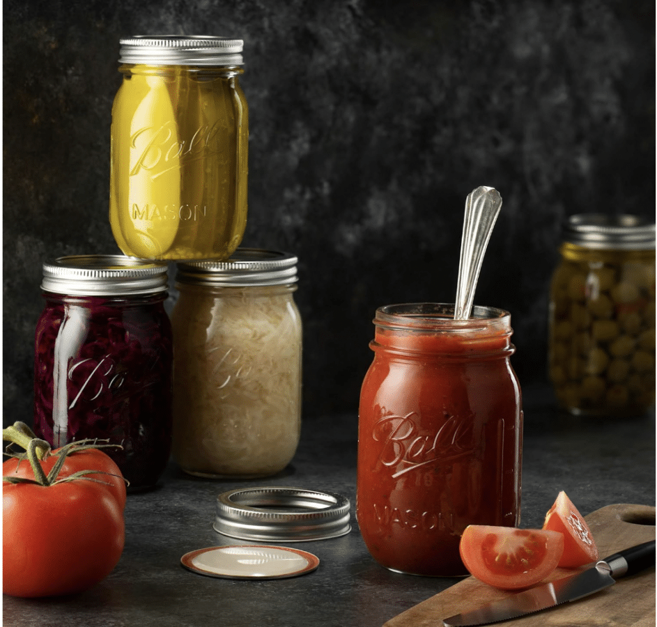 mason jars containing various produce artfully arranged on a dark backdrop