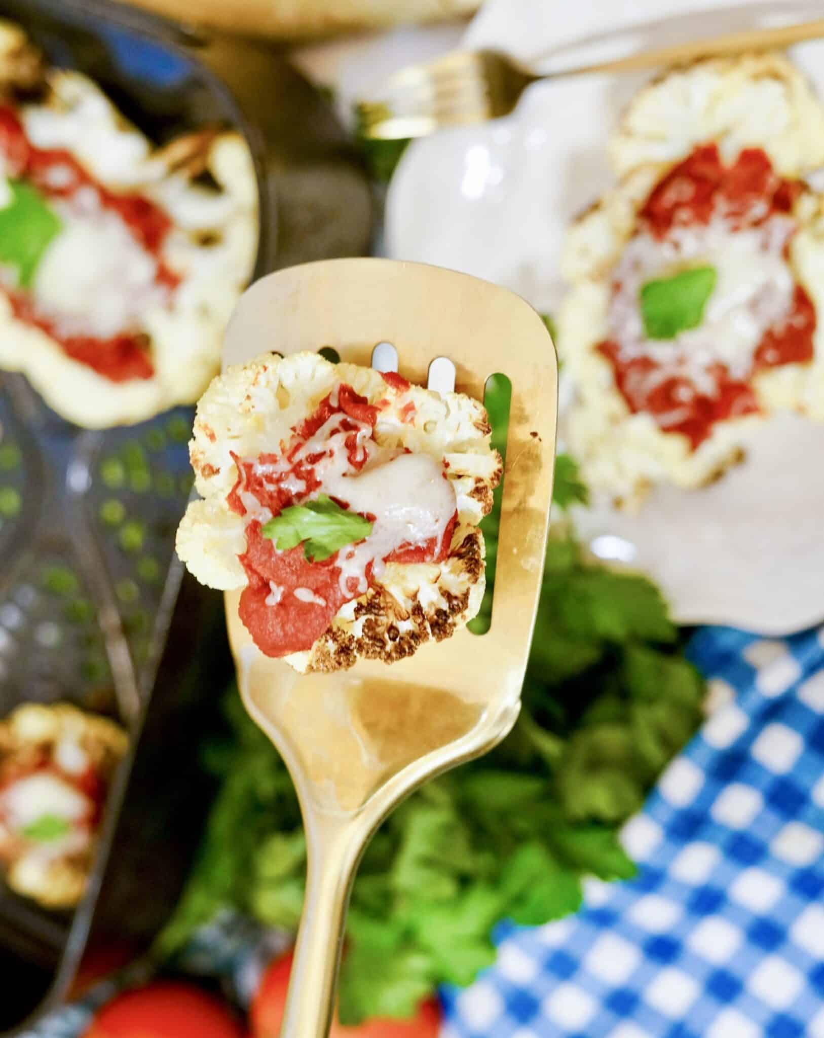 A golden spatula with a piece of air fryer cauliflower parmesan.