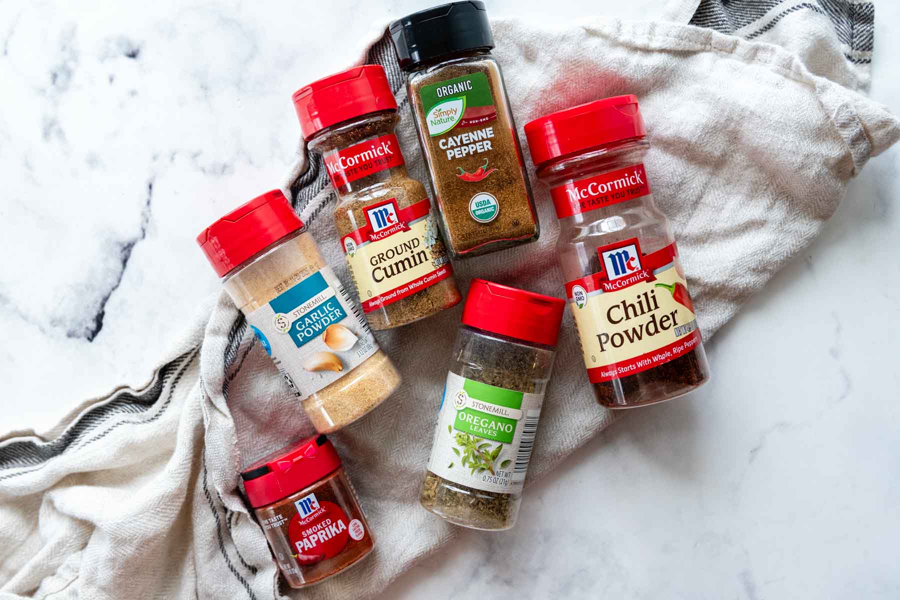 spices used to make taco seasoning on a white background.