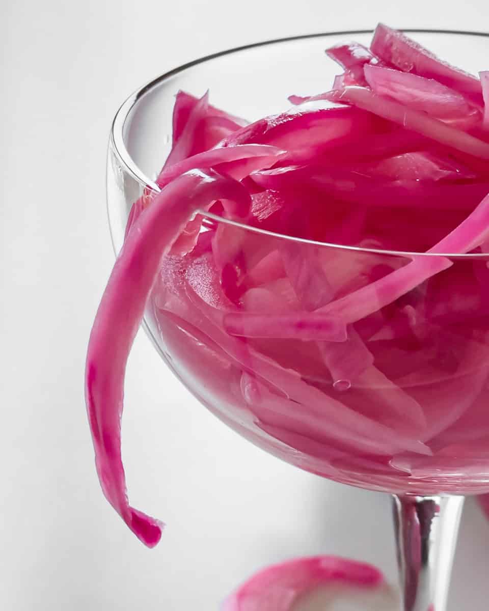 Quick pickled red onions i a coupe glass.