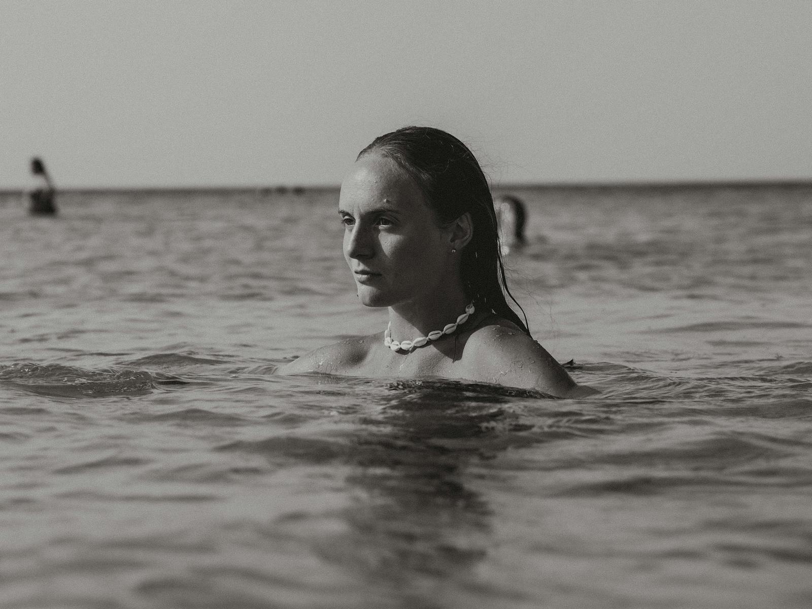A captivating black and white portrait of a woman swimming in the ocean.
