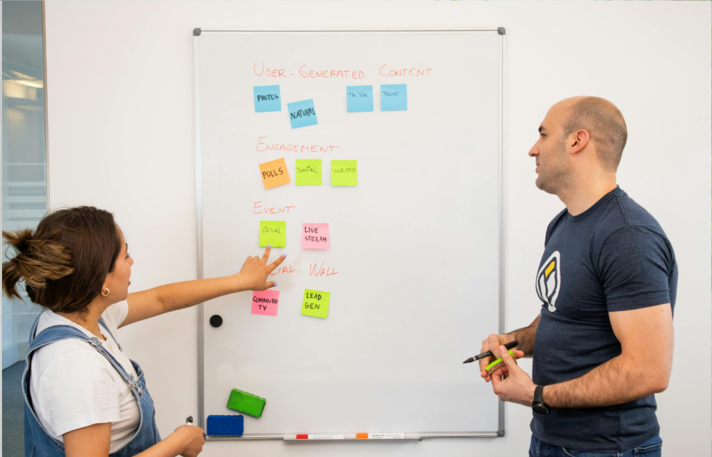 A manager leading person with sticky notes on a whiteboard