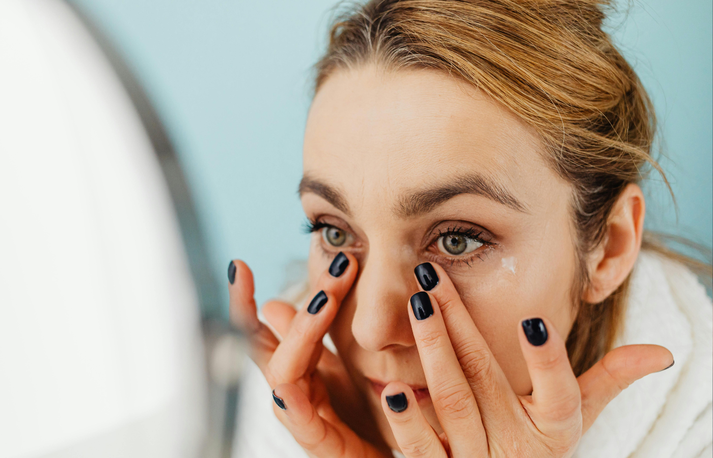 A Woman applying cream in front of a mirror Her Face