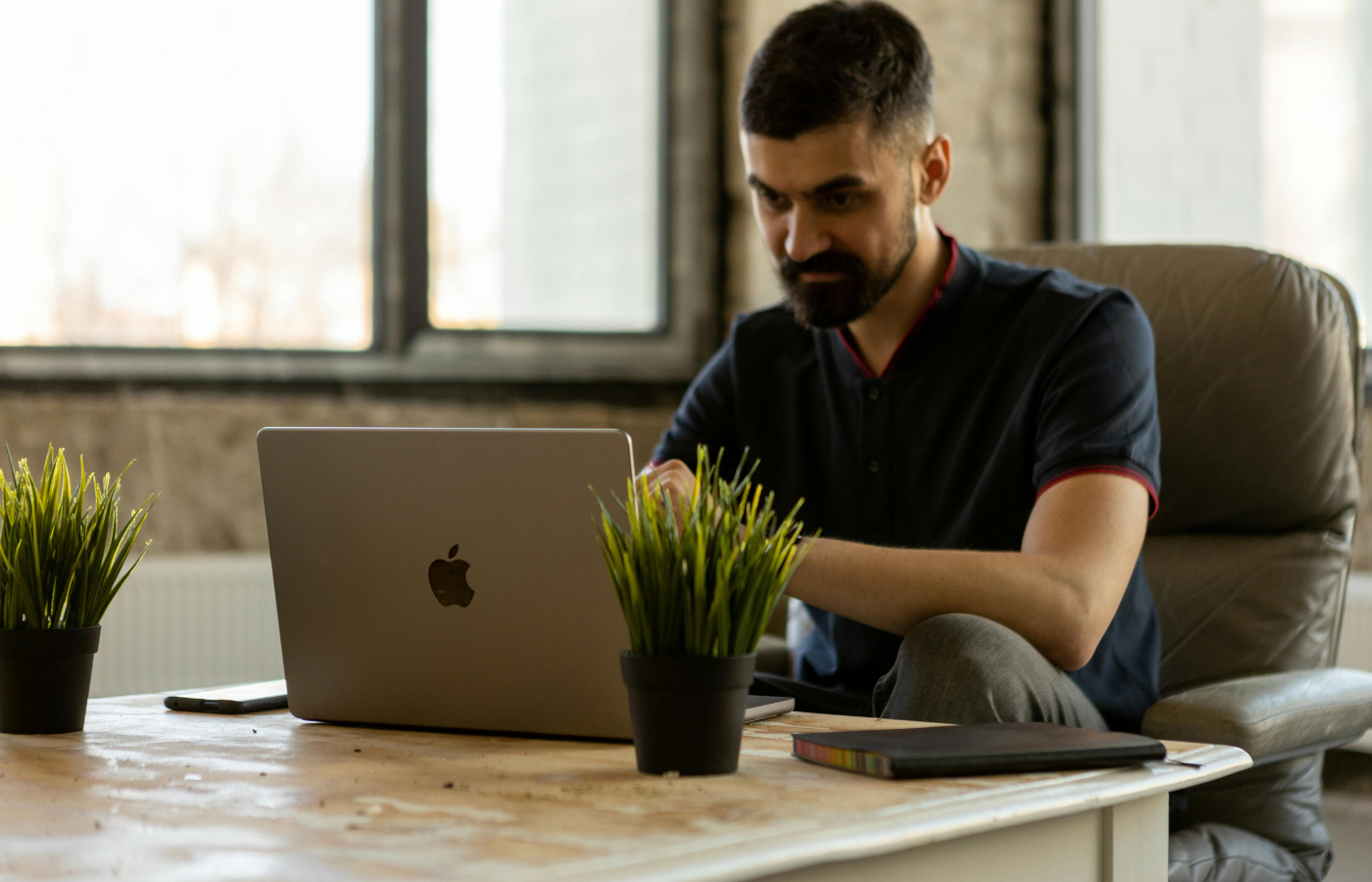 A Man Sitting on the Chair while Using His Laptop