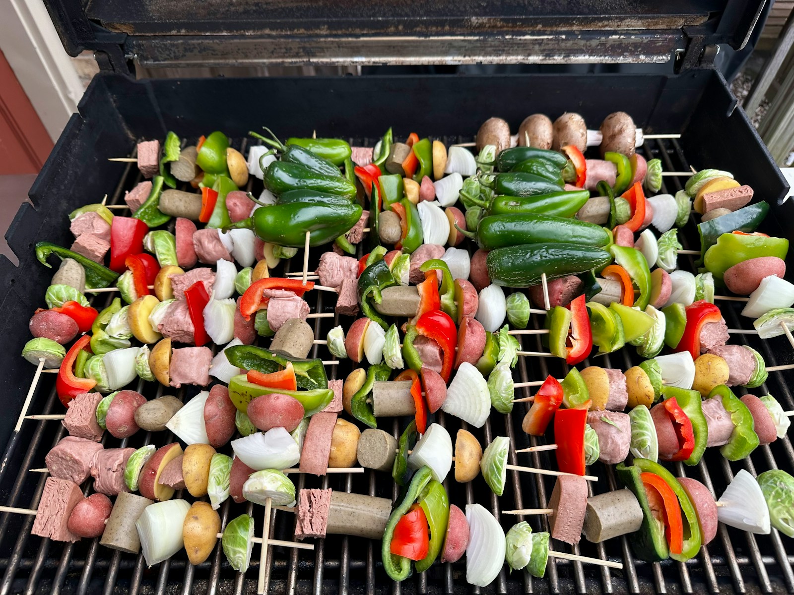 Skewers with meat and vegetables cooking on a grill.