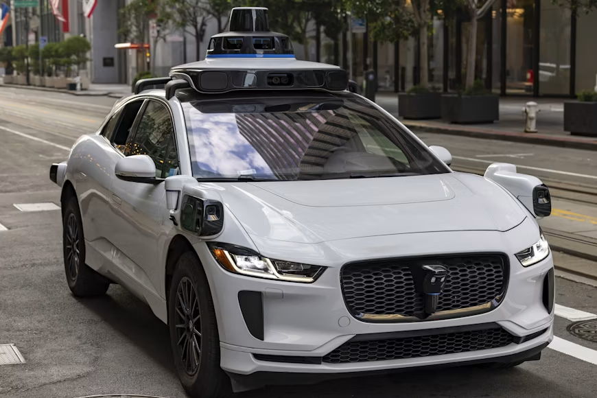 Robotaxi with roof-mounted sensors driving on a city street.