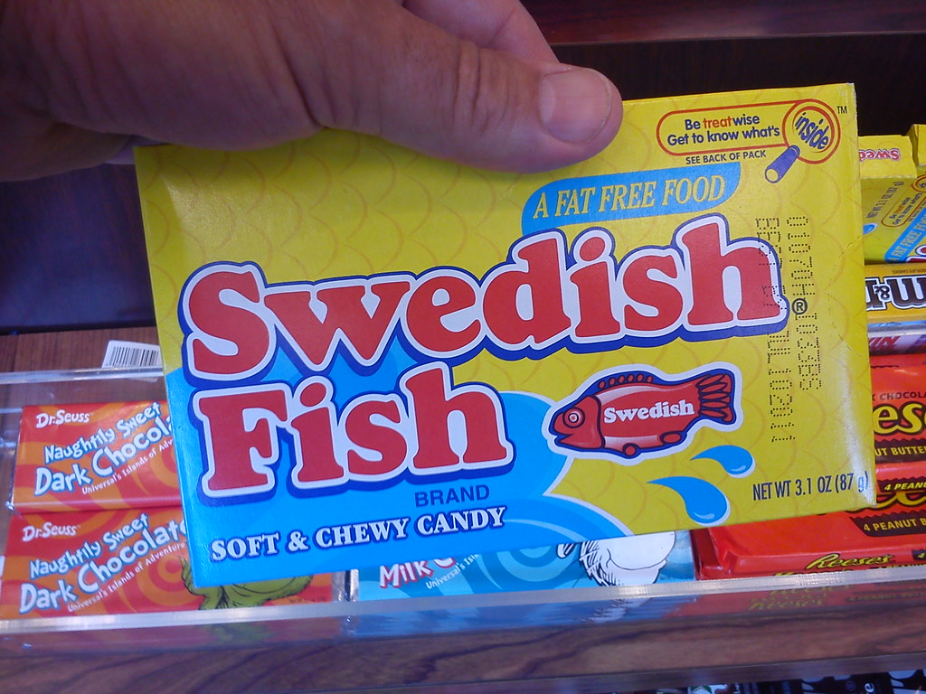 Hand holding a Swedish Fish candy, popular in America but unknown in Sweden