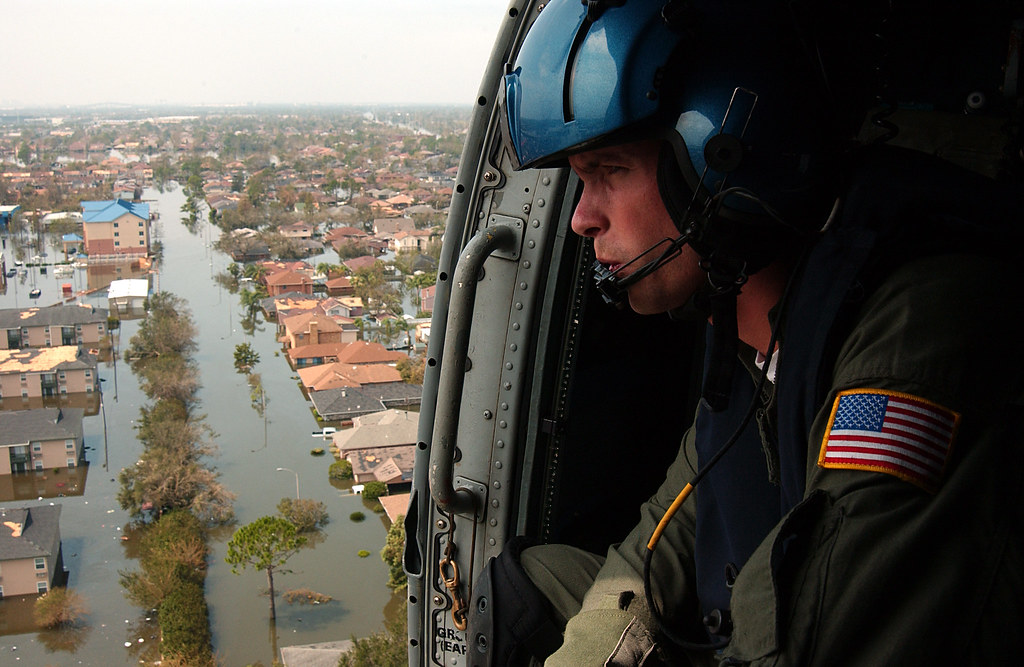 A Coastie keeps a sharp lookout from a helicopter over flooded New Orleans